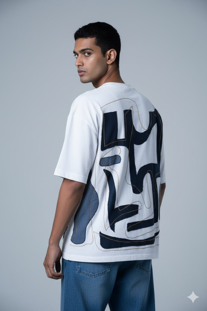 Man wearing a white t-shirt with black abstract designs on the back against a gray background