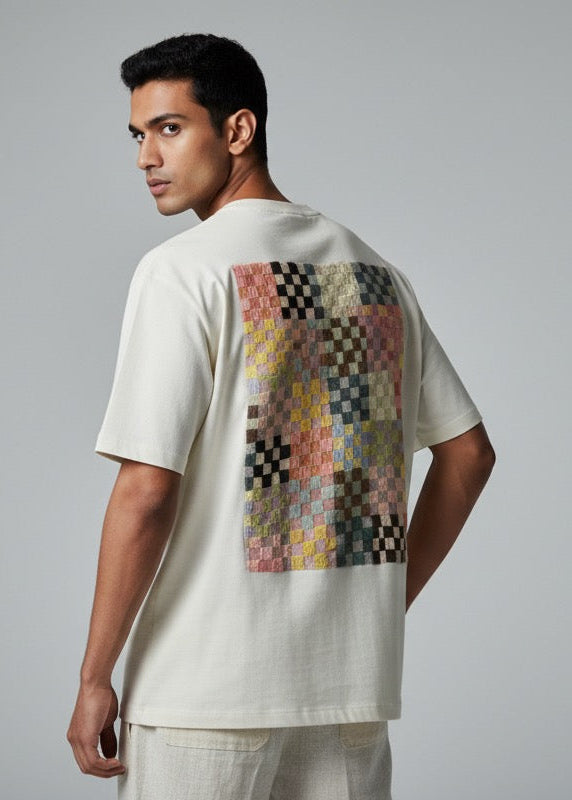 Man wearing a white t-shirt with a colorful pattern on the back against a gray background