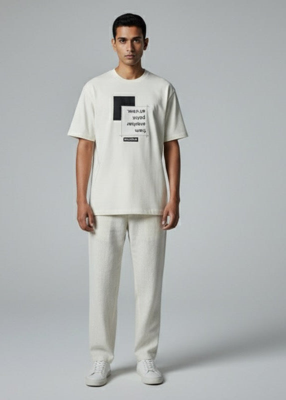 Person wearing a white t-shirt and pants with a logo on a gray background
