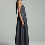Woman wearing a gray dress with cargo pockets on a plain background