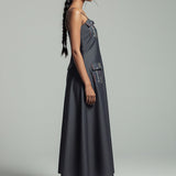 Woman wearing a gray dress with cargo pockets on a plain background