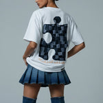 Person wearing a white t-shirt with a black and gray design, blue skirt, and blue knee-high boots on a gray background