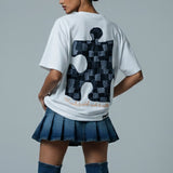 Person wearing a white t-shirt with a black and gray design, blue skirt, and blue knee-high boots on a gray background