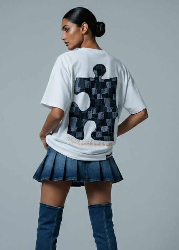 Person wearing a white t-shirt with a black and gray design, blue skirt, and blue knee-high boots on a gray background