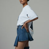 Woman wearing a white t-shirt and denim skirt on a gray background