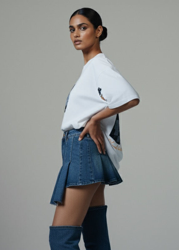 Woman wearing a white t-shirt and denim skirt on a gray background
