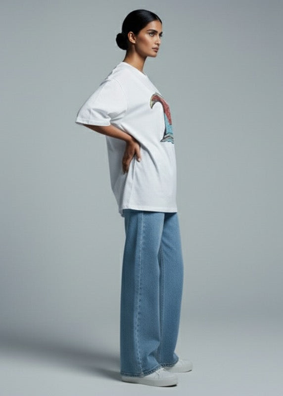Woman wearing a white shirt and light blue pants against a gray background