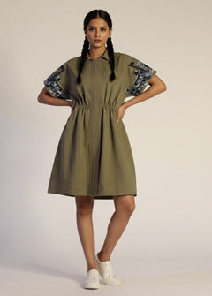 Woman wearing a green dress with floral sleeves on a plain background