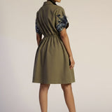 Woman wearing a green dress with blue patterns on a beige background