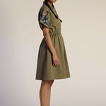 Woman wearing a green dress with floral sleeves on a plain background