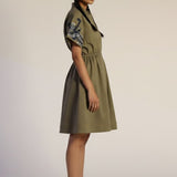 Woman wearing a green dress with floral sleeves on a plain background