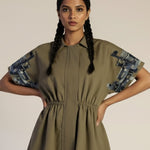 Woman wearing a green dress with patterned sleeves on a beige background