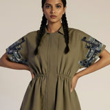 Woman wearing a green dress with patterned sleeves on a beige background