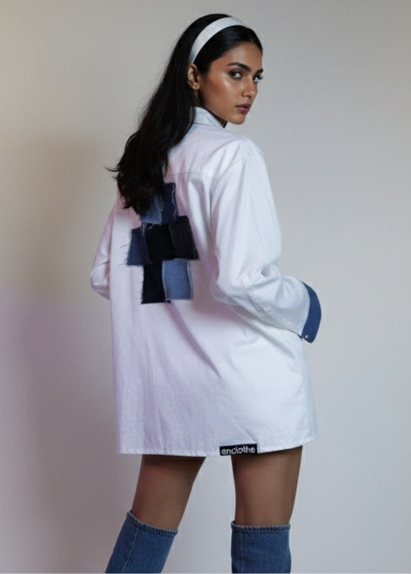 Woman wearing a white outfit with blue accents on a plain background