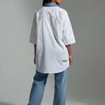 Person wearing a white lab coat and blue jeans on a plain background