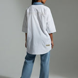 Person wearing a white lab coat and blue jeans on a plain background