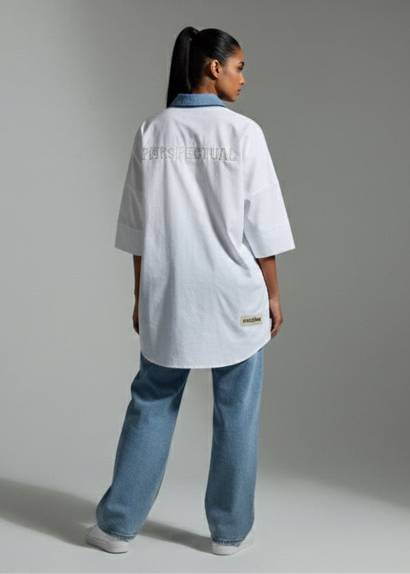 Person wearing a white lab coat and blue jeans on a plain background