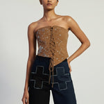 Woman wearing a strapless top and dark pants with geometric patterns on a plain background