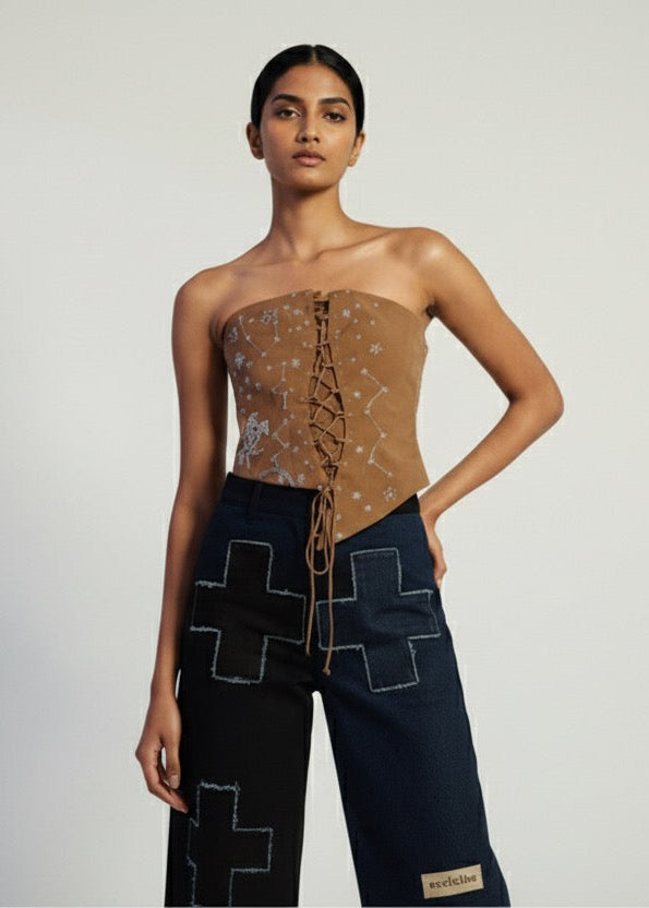 Woman wearing a strapless top and dark pants with geometric patterns on a plain background