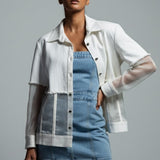 Woman wearing a white shirt over a denim dress on a gray background