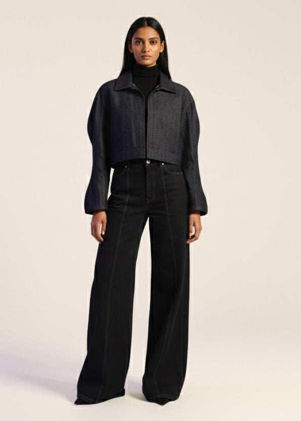 Woman wearing a black outfit with a jacket and pants on a plain background