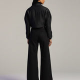 Person wearing a black outfit on a plain background