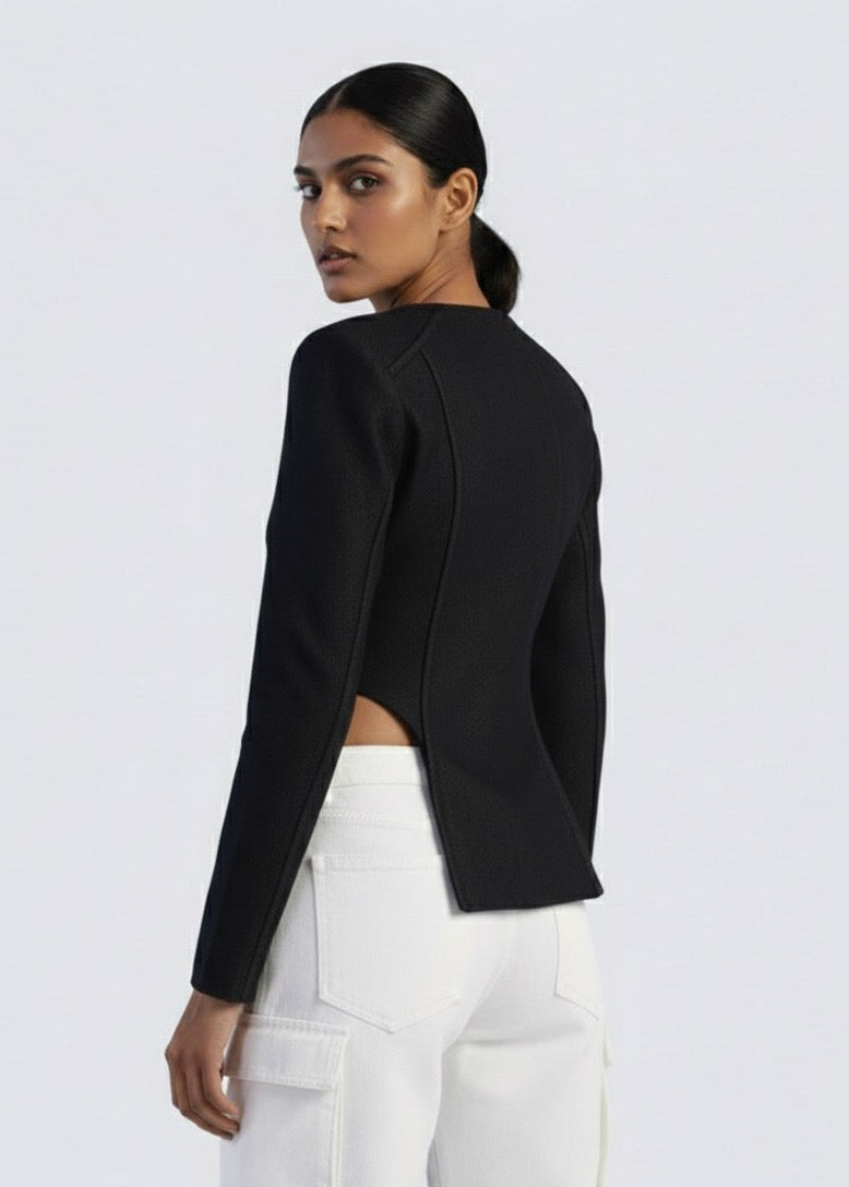 Woman wearing a black cropped jacket and white pants on a light gray background