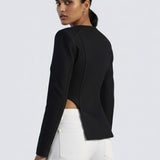 Woman wearing a black cropped jacket and white pants on a light gray background