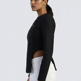 Woman wearing a black blazer and white pants on a light gray background
