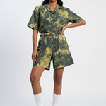 Woman wearing a green and yellow tie-dye outfit on a white background