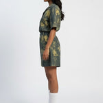 Woman wearing a green and brown patterned dress on a white background