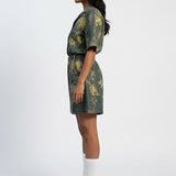 Woman wearing a green and brown patterned dress on a white background