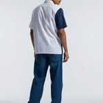 Man wearing a white and blue polo shirt with jeans on a white background