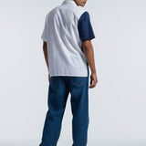 Man wearing a white and blue polo shirt with jeans on a white background