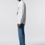 Man wearing a white shirt and blue jeans standing against a plain background