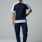Man wearing a black and white polo shirt with blue pants on a gray background