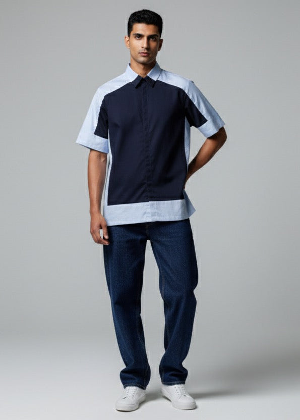 Man wearing a black and white polo shirt with blue pants on a gray background