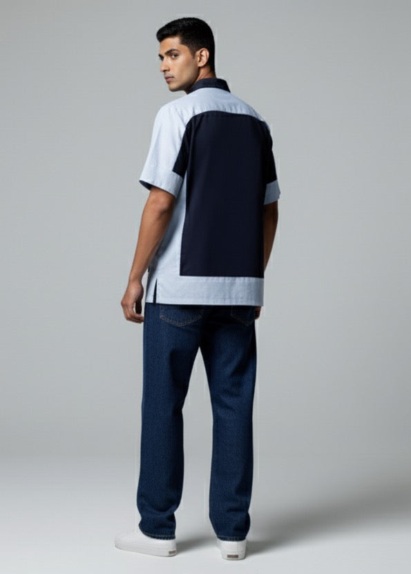 Man wearing a white and navy striped shirt with dark jeans on a gray background