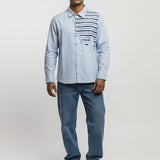 Man wearing a light blue shirt with a patterned vest, jeans, and white sneakers on a white background