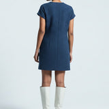 Woman wearing a blue dress and white boots on a light gray background