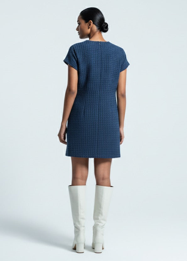 Woman wearing a blue dress and white boots on a light gray background