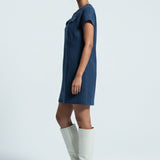 Woman wearing a blue dress and white knee-high boots on a light gray background