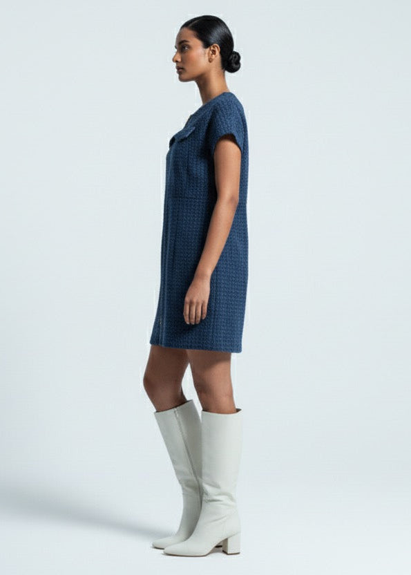 Woman wearing a blue dress and white knee-high boots on a light gray background