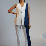 Woman wearing a sleeveless top and pants with a blue accent on a plain background