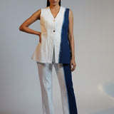 Woman wearing a sleeveless top and pants with a blue accent on a plain background