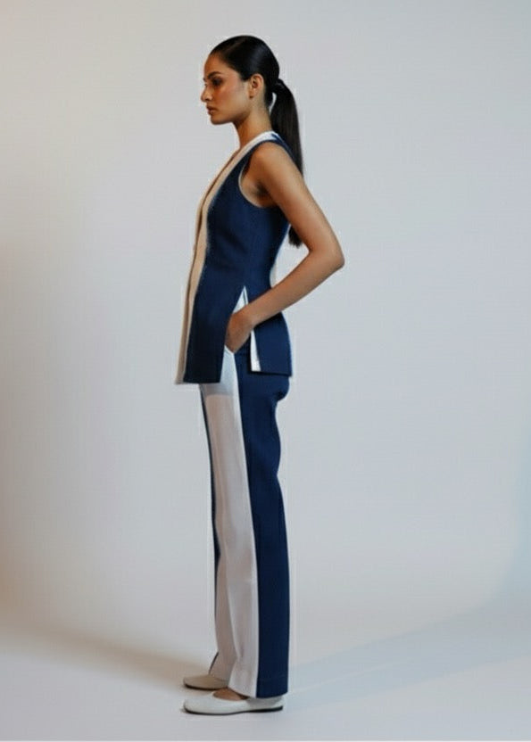 Woman wearing a navy blazer and light gray pants on a white background
