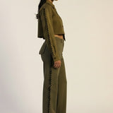 Woman wearing a green outfit with zippers on a plain background