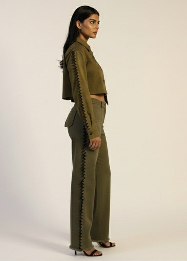 Woman wearing a green outfit with zippers on a plain background