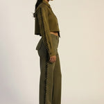 Woman wearing a green outfit with zippers on a plain background