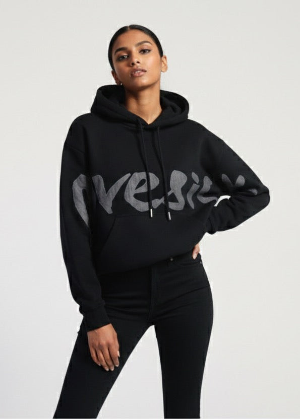 Person wearing a black hoodie with 'Versace' branding on a light gray background